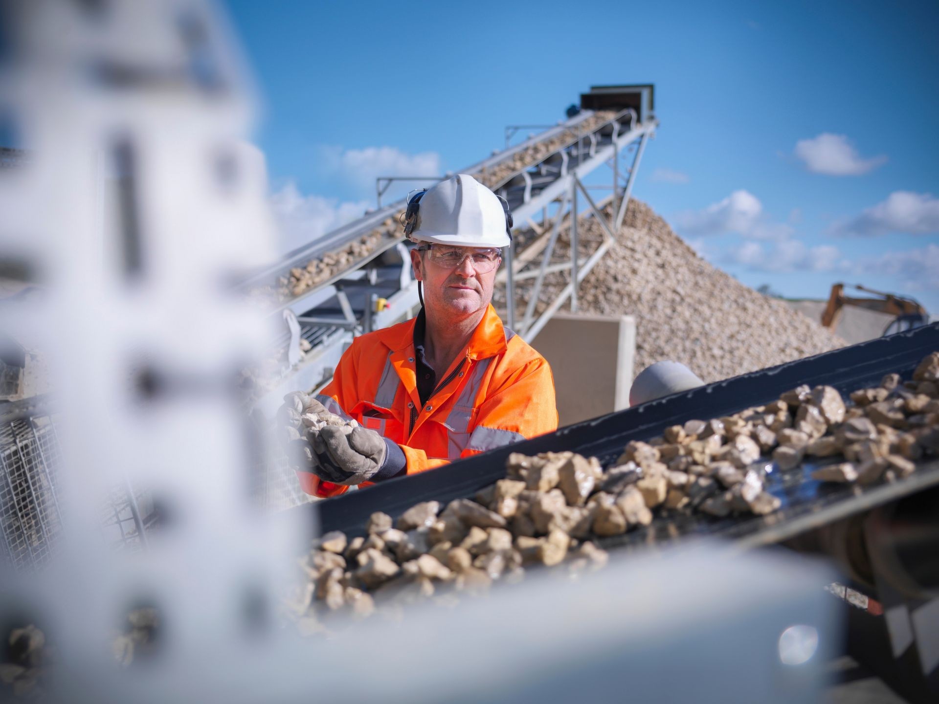 Worker inspecting stone screening and crushing machine in quarry